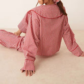 Person wearing a red and white checkered outfit sitting on a beige surface.